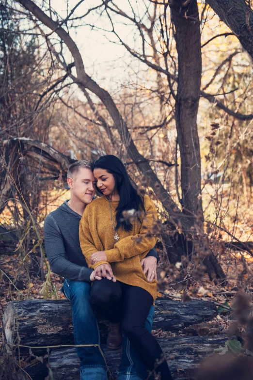 a man and woman sitting on a log in the woods, a portrait, pexels contest winner, holding each other, low quality photo, fall season, february)