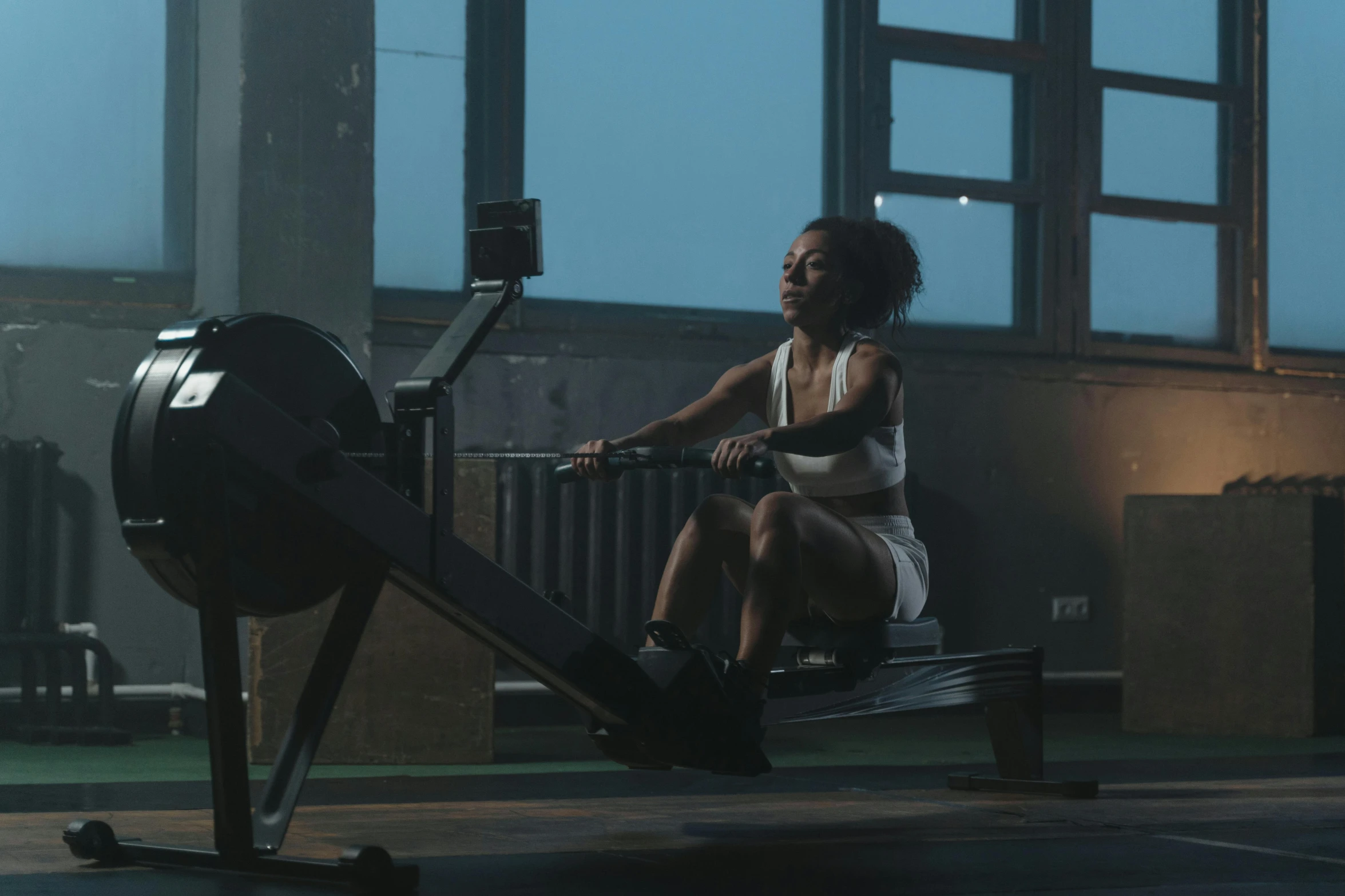 a woman sitting on a rowing machine in a gym, pexels contest winner, low light cinematic, photo of a black woman, promo image, thumbnail