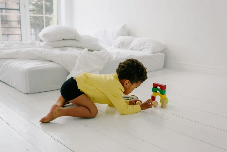 a young child playing with blocks on the floor, pexels contest winner, in white room, scarlet and yellow scheme, looking at his phone, a wooden