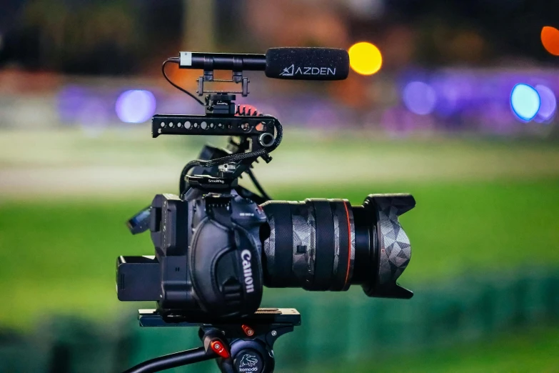 a close up of a camera on a tripod, looking towards the camera, video camera, sports broadcast, facing away from the camera