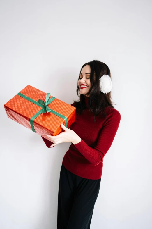 a woman in a santa hat holding a gift, pexels contest winner, with head phones, wearing an orange jumpsuit, wearing turtleneck, gif