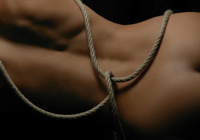 a woman is tied up with a rope, an album cover, inspired by Roberto Ferri, pexels contest winner, tanned skin, upper body close - up, 6 pack ab, smooth textured skin