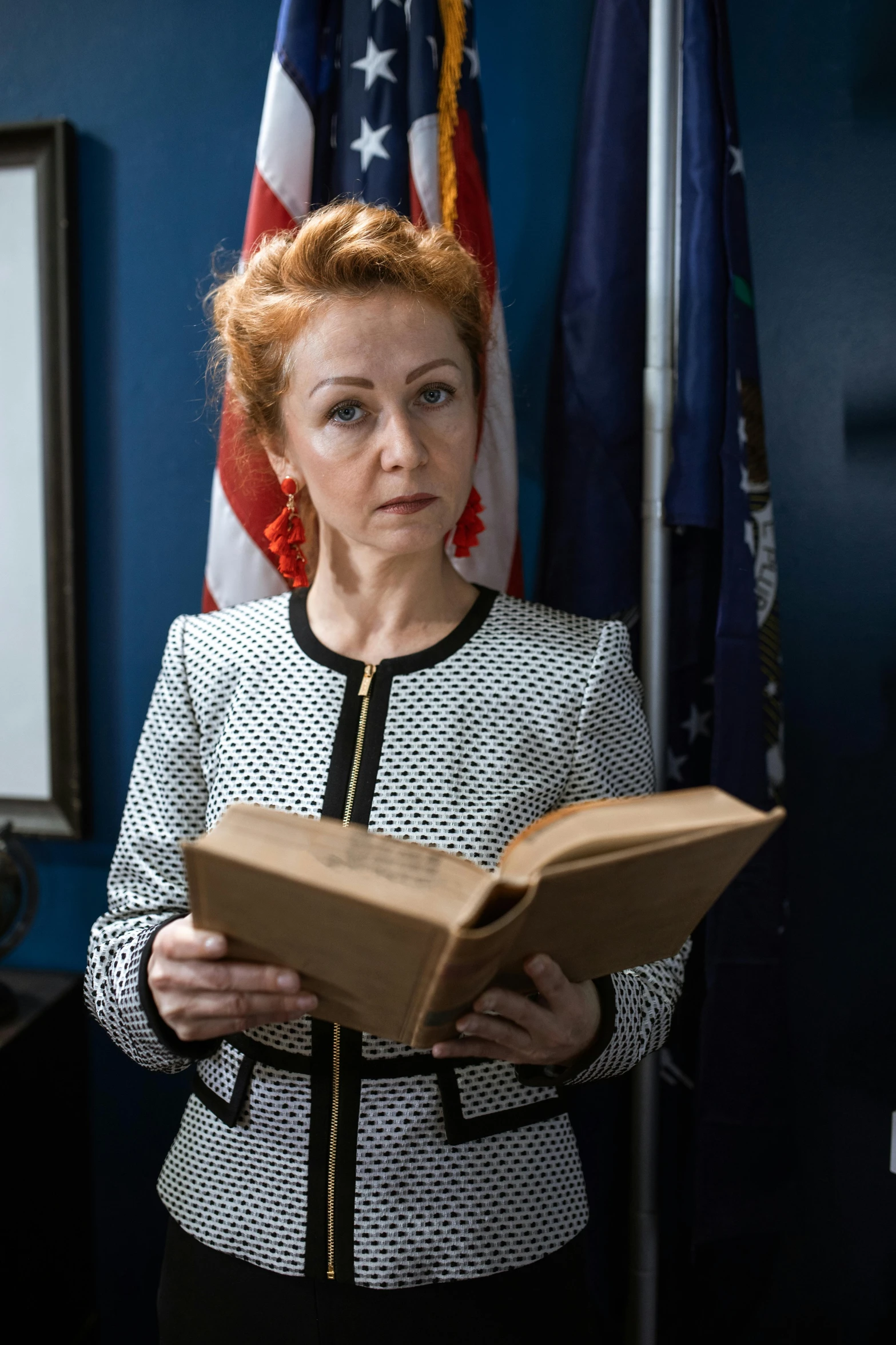 a woman reading a book in front of an american flag, inspired by Nil Gleyen, trending on reddit, private press, redhead woman, production still, courtroom scene, in australia