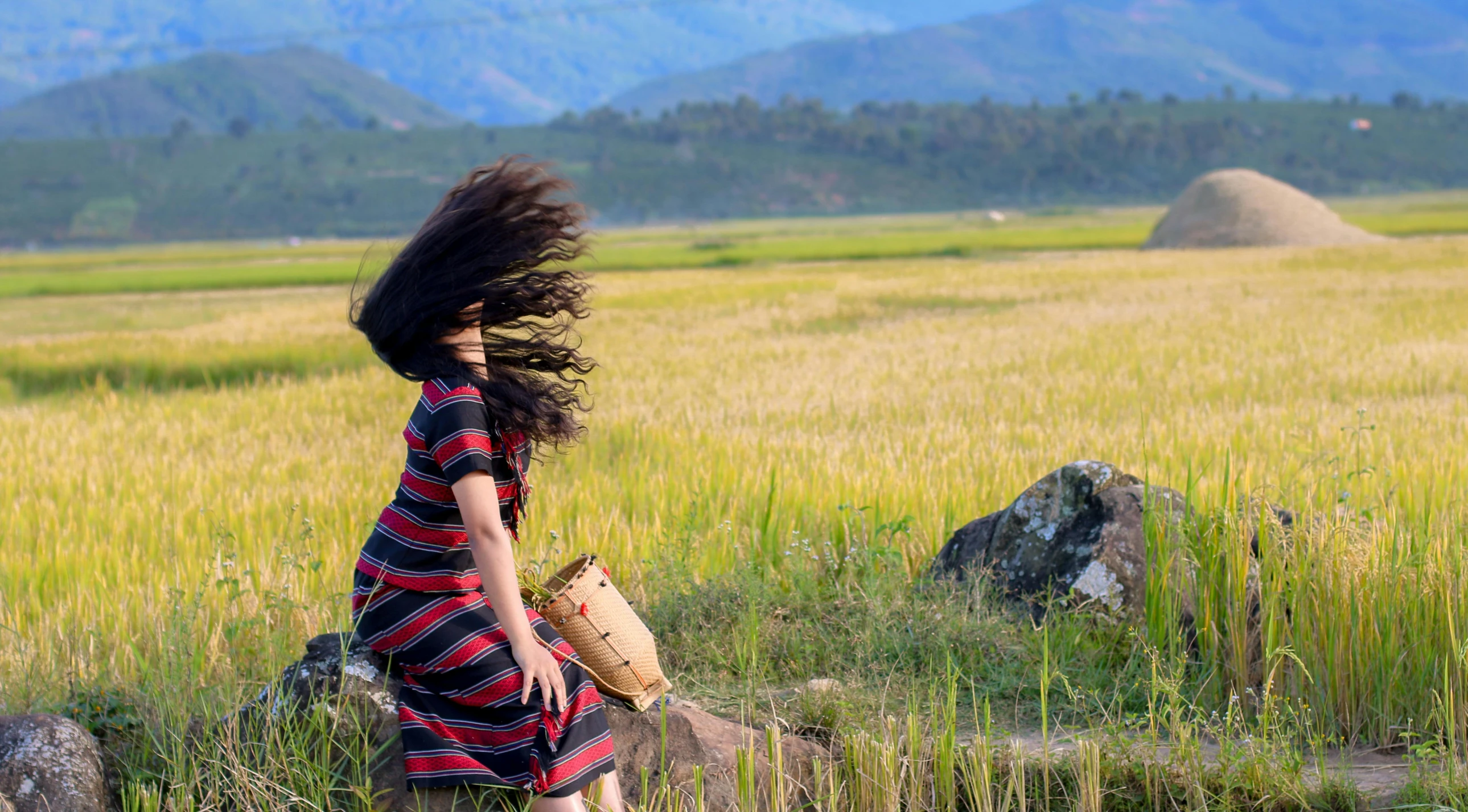 a woman walking across a lush green field, an album cover, inspired by Steve McCurry, pexels contest winner, hair blowing the wind, vietnamese woman, profile image, headbanging