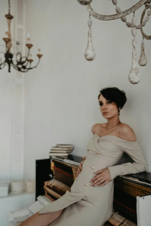 a woman sitting on top of a table next to a chandelier, pexels contest winner, rococo, with black hair, maternity feeling, photo of džesika devic, with short hair