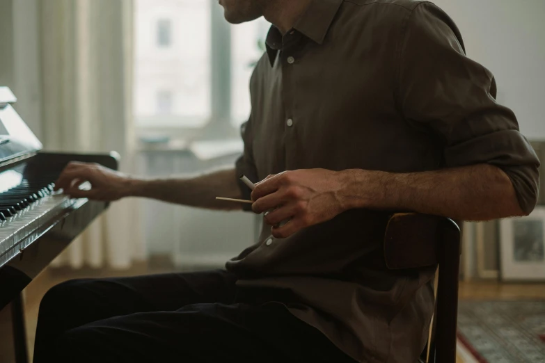 a man that is sitting in front of a piano, unsplash, brown shirt, office clothes, sitting on an armchair, hyperdetailed photo