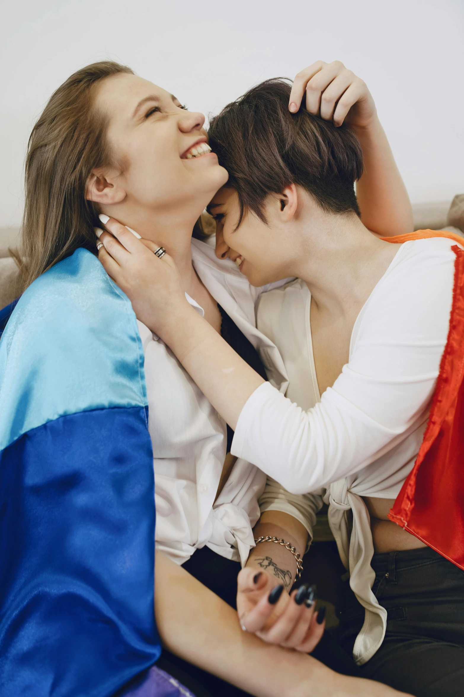 a couple of women sitting on top of a couch, by Arabella Rankin, trending on pexels, french flag, wearing shoulder cape, lesbian embrace, marat zakirov