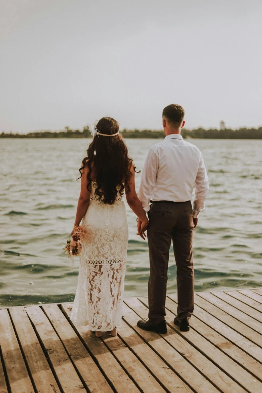 a bride and groom standing on a dock looking out at the water, pexels contest winner, afternoon hangout, islands, hands pressed together in bow, queen