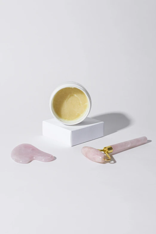 a jar of cream sitting on top of a white table, gold mask, rose quartz, detailed product image, pestle