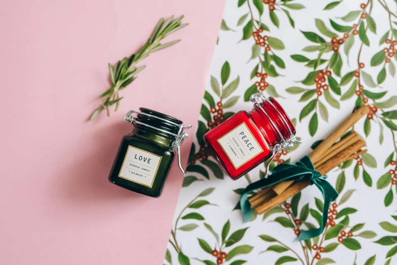 a couple of candles sitting on top of a table, viridian and venetian red, loputyn and matcha, miniature product photo, evergreen branches