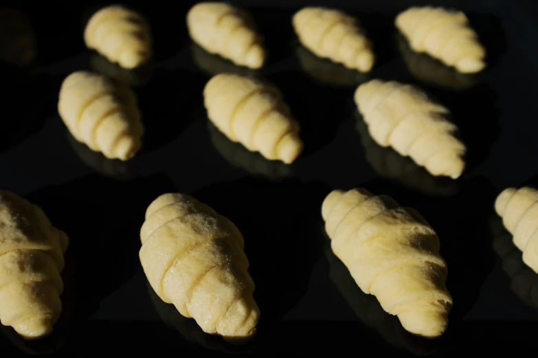 a tray filled with croissants sitting on top of a table, inspired by Károly Patkó, process art, in front of a black background, thumbnail, cone heads, made in blender