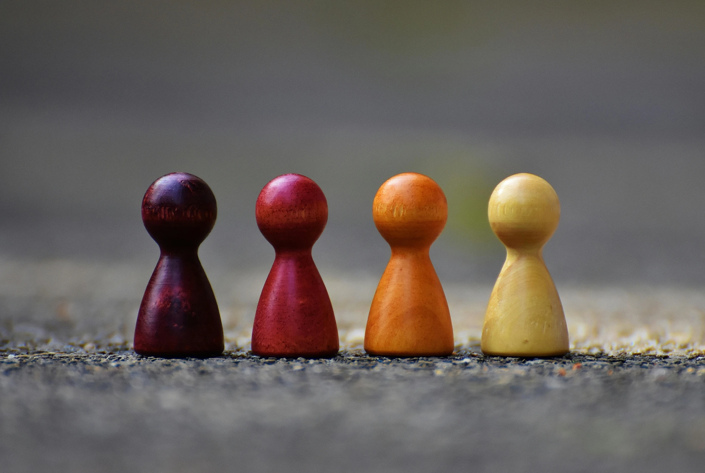 a row of wooden pegs sitting next to each other, a picture, unsplash, figuration libre, game characters, standing in road, 4 colors, dark grey and orange colours