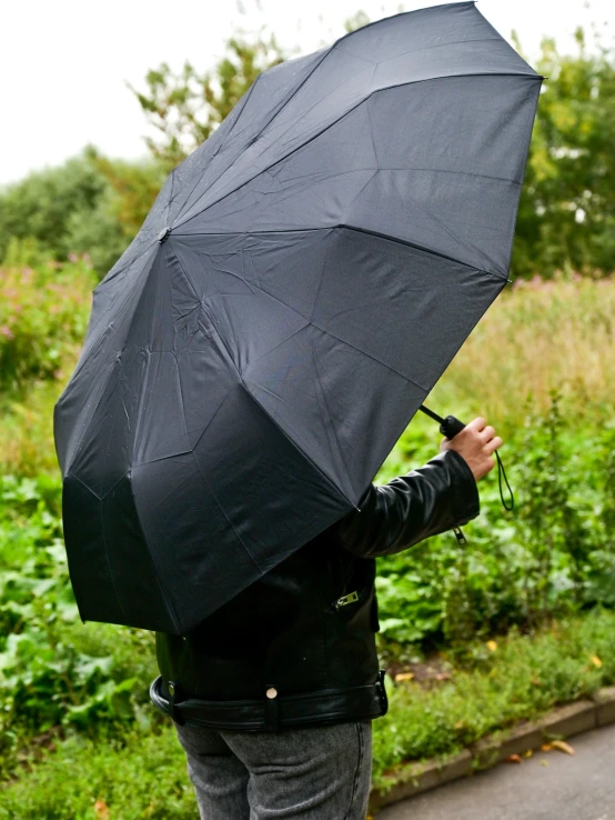 a person standing on the side of a road holding an umbrella, black matte finish, detailed product shot, modeled