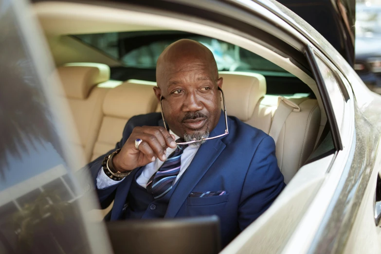 a man in a blue suit sitting in a car, huell babineaux, high res photograph, an oldman, avatar image