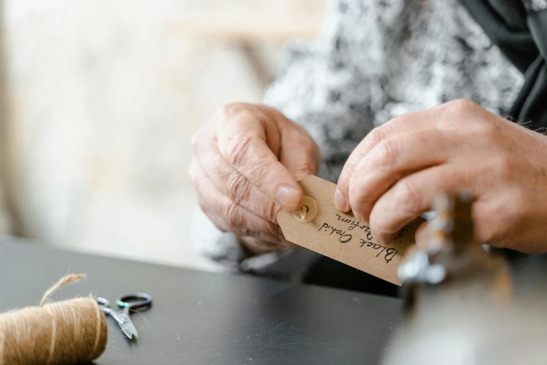 a person cutting a piece of wood with a pair of scissors, by Sylvia Wishart, pexels contest winner, label, an elderly, made from paper, lightly dressed