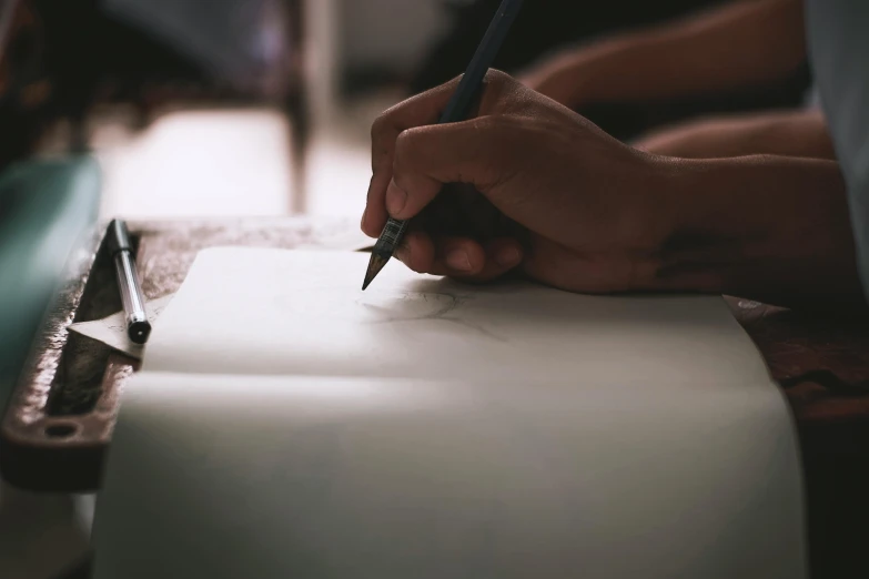 a person writing on a piece of paper with a pencil, a drawing, by Robbie Trevino, pexels contest winner, academic art, background image, indian ink, fan favorite, creating a soft