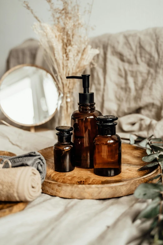 a wooden tray sitting on top of a bed next to a mirror, a still life, unsplash, bottles covered in wax, detailed product image, brown, eco