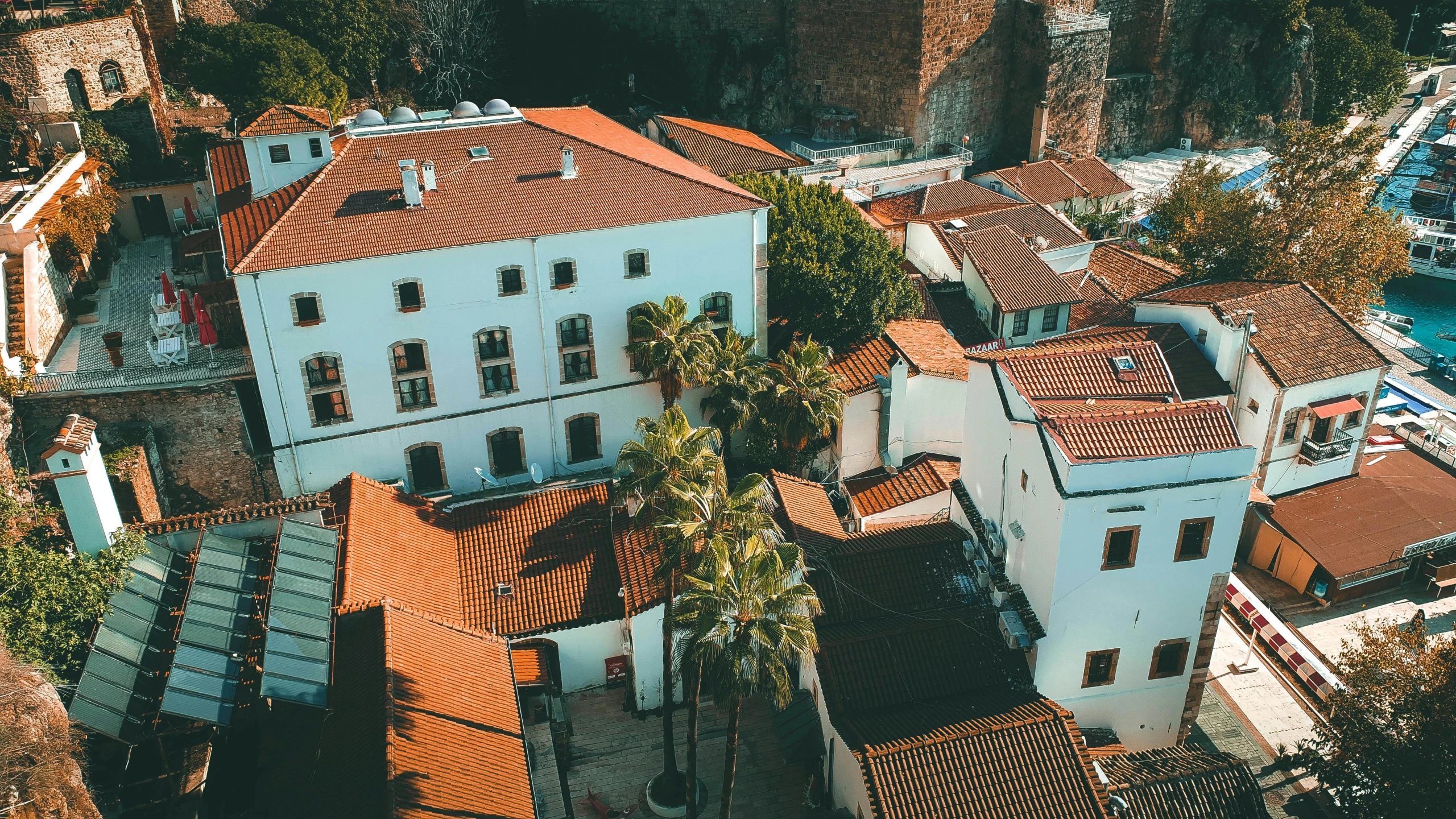 a large white building sitting on top of a lush green hillside, pexels contest winner, gothic quarter, orange roof, top down view, courtyard