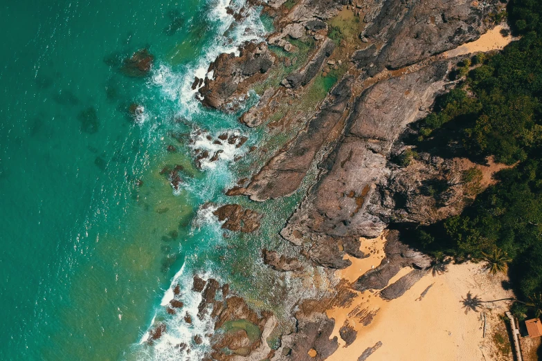 a large body of water next to a sandy beach, by Lee Loughridge, pexels contest winner, airborne view, rocky coast, teal and orange colours, hd footage