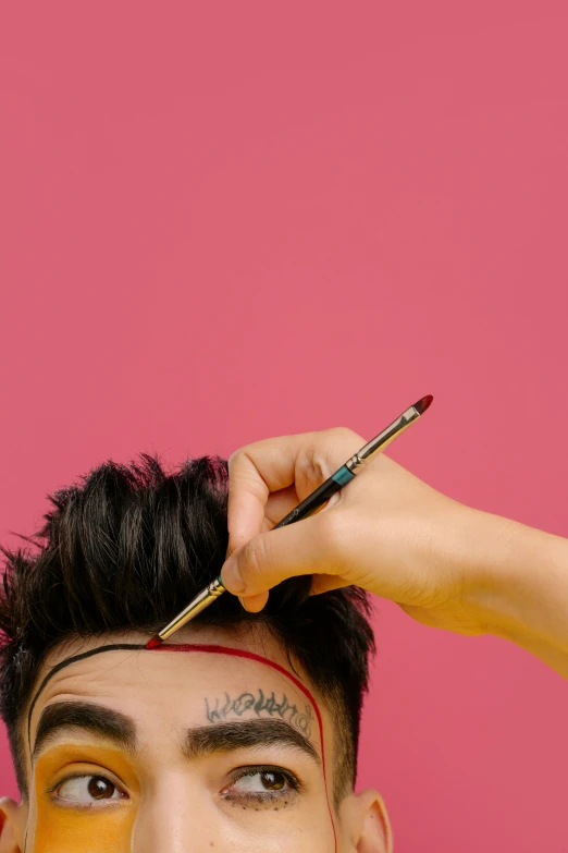 a man that has some paint on his face, an album cover, trending on pexels, holding pencil, back of the hair, pink and red color scheme, androgynous