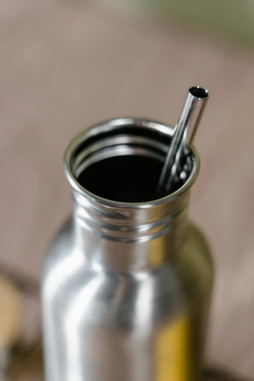 a metal bottle with a straw sticking out of it, bespoke, zoomed in, spoon placed, environmental shot