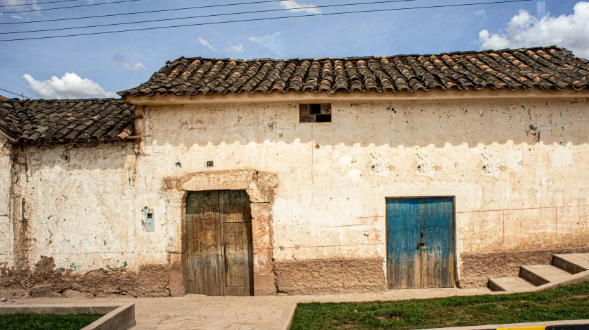 an old building with a blue door in front of it, an album cover, unsplash, arte povera, 1 8 th century south america, farmhouse, background image