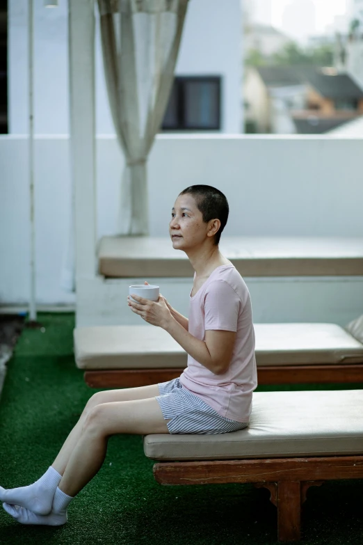 a man sitting on top of a wooden bench, a portrait, inspired by Fei Danxu, pexels contest winner, woman drinking coffee, partially bald, hotel room, vietnam