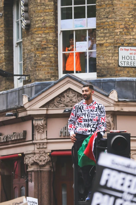 a man sitting on top of a traffic light, by Nina Hamnett, trending on unsplash, patterned clothing, an arab standing watching over, in london, promotional image