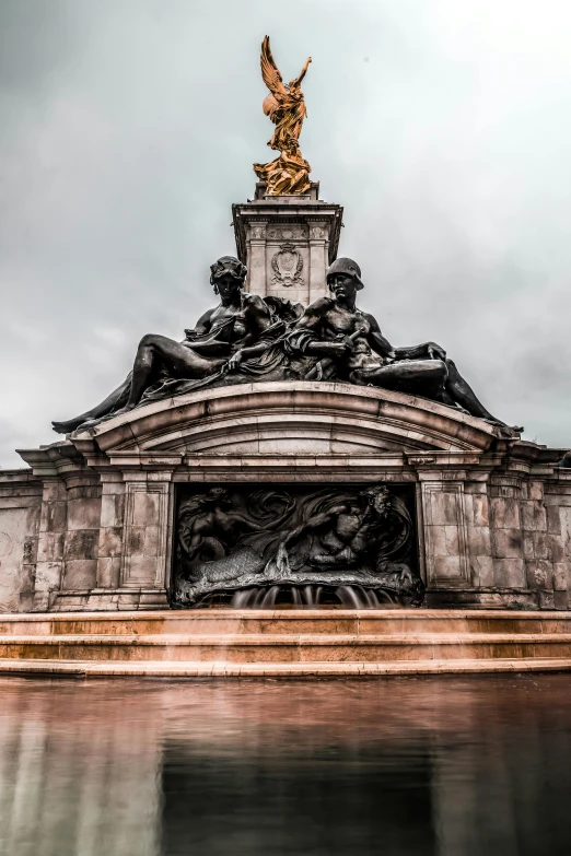 a statue on top of a building next to a body of water, a statue, fountains and arches, london, huge gate, rainy