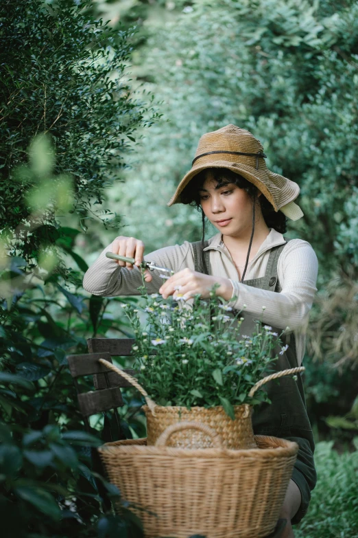 a woman sitting on a bench with a basket of plants, inspired by Ruth Jên, pexels contest winner, renaissance, picking flowers, with hat, mai anh tran, standing in a botanical garden