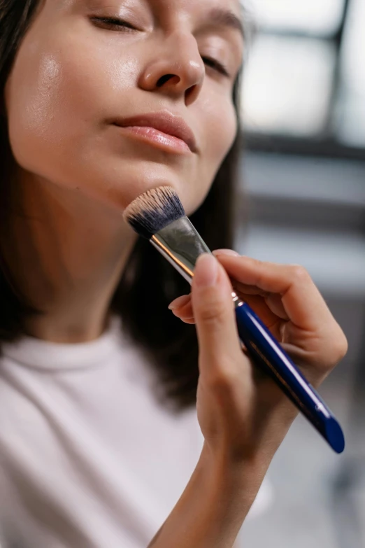 a woman brushes her face with a brush, trending on pexels, hyperrealism, textured base ; product photos, navy, multi - layer, blue