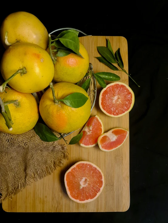 a bunch of grapefruits sitting on top of a cutting board, by Jan Tengnagel, with a black background, 王琛, portrait n - 9, malaysian