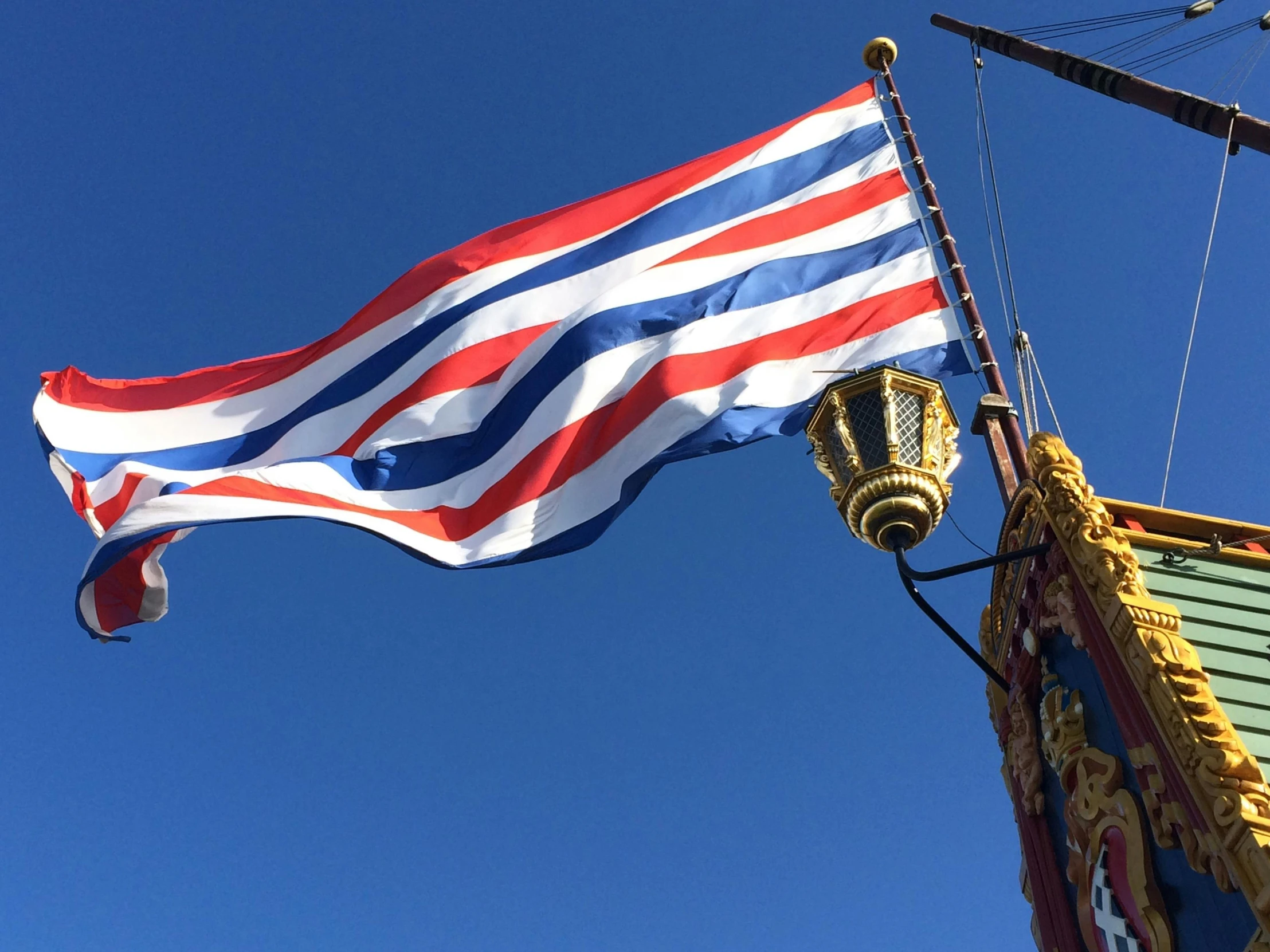 a large red, white and blue flag flying in the air, hurufiyya, gold galleon ship, bangkok townsquare, profile image, square