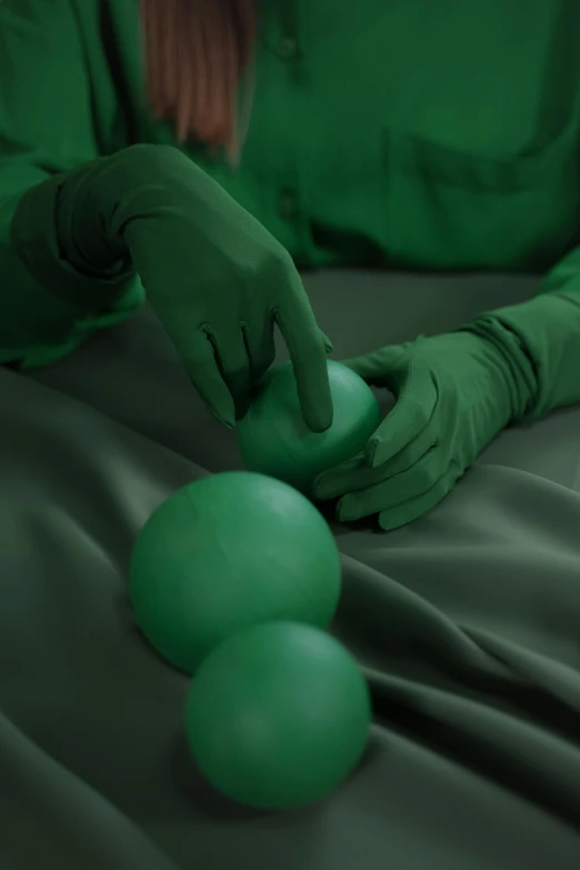 a close up of a person wearing green gloves, an album cover, inspired by Art Green, deviantart, surrealism, floating spheres and shapes, clay animation, laying down with wrists together, performance art