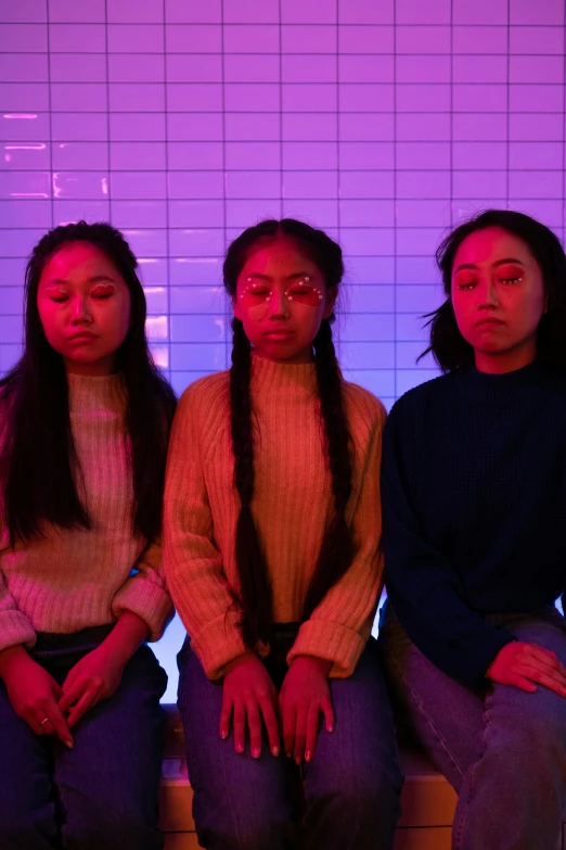 a group of women sitting next to each other, an album cover, trending on pexels, aestheticism, with neon lights, three heads, asian descent, ((purple))