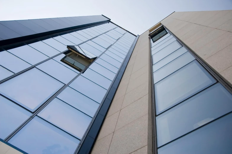 a couple of tall buildings next to each other, a photo, inspired by Tadao Ando, unsplash, bauhaus, steel window mullions, looking upwards, close up shot from the side, high quality photo