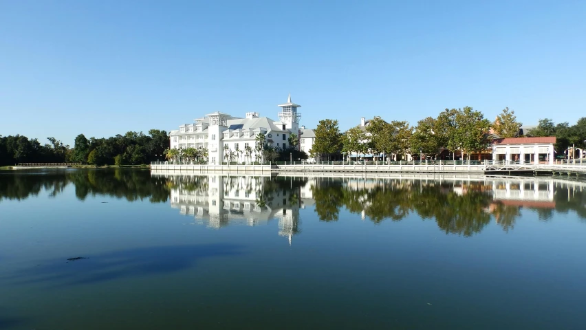 a large white building sitting on top of a lake, inspired by Pedro Álvarez Castelló, jerez, a park, blue sky, mirror lake