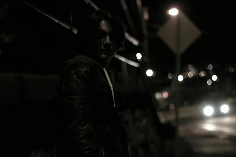 a man standing on the side of a road at night, an album cover, inspired by Jorge Jacinto, pexels contest winner, wearing cyberpunk leather jacket, in an alley at night back lit, dark monochrome, superhero from the boys tv show