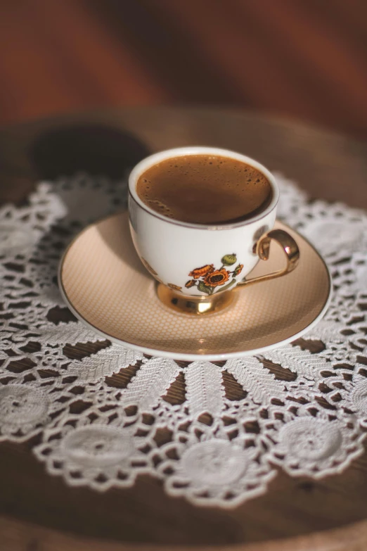 a cup of coffee sitting on top of a saucer, on a table