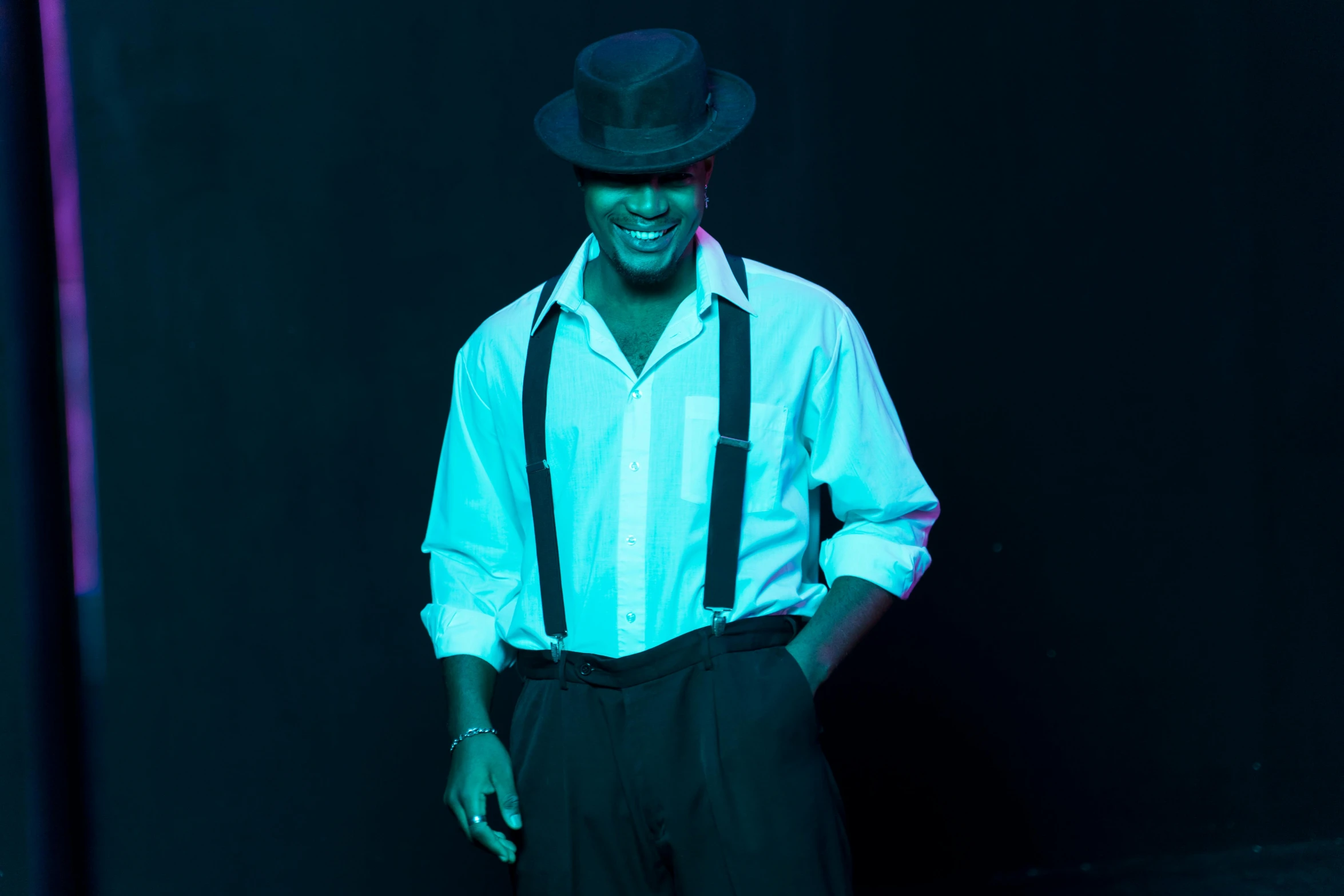 a man with a hat and suspenders posing for a picture, in the spotlight, jamal campbell, press photos, ( ( dark skin ) )