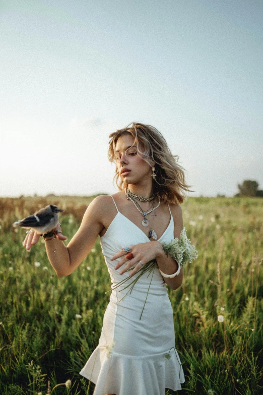 a woman standing in a field holding a bird, inspired by Elsa Bleda, trending on pexels, jewelry, portrait sophie mudd, concert, in field high resolution