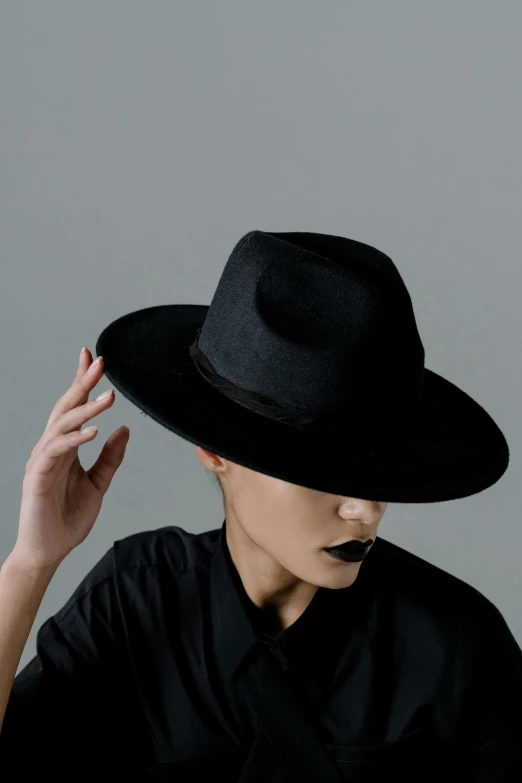 a woman wearing a black hat and a black shirt, an album cover, trending on pexels, faded fedora, front top side view, black horns, viewed from the side