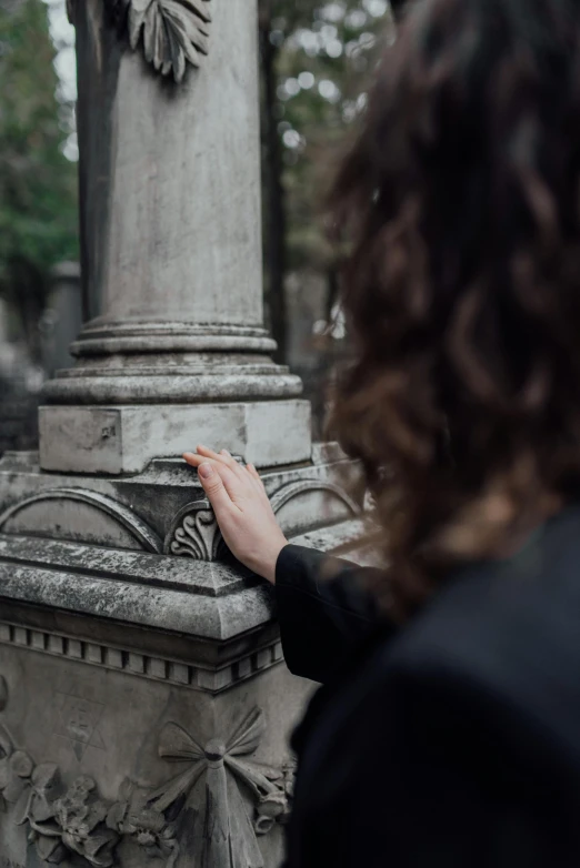 a woman looking at a statue in a cemetery, pexels contest winner, pointing, pillar, subtle detailing, lgbtq