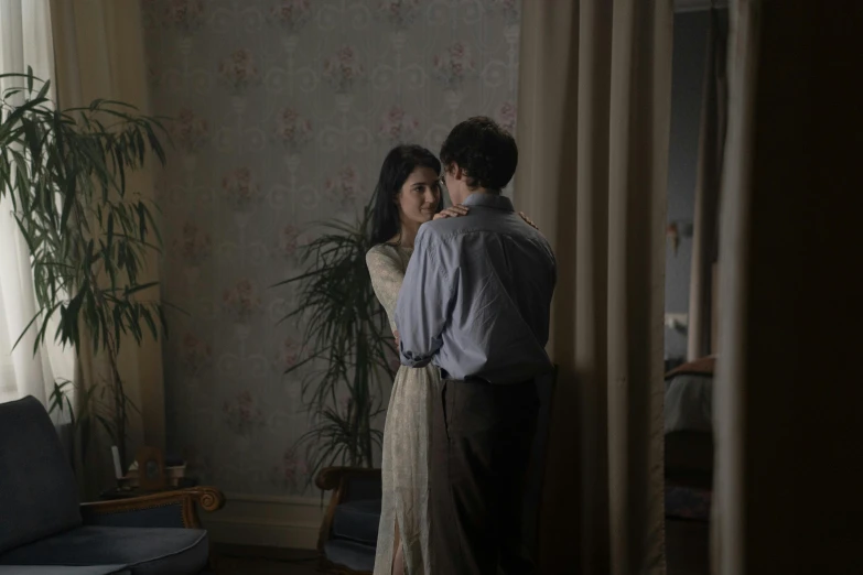a man standing next to a woman in a living room, by Jaakko Mattila, pexels contest winner, serial art, movie still frame, romantic lead, standing in corner of room, low colour