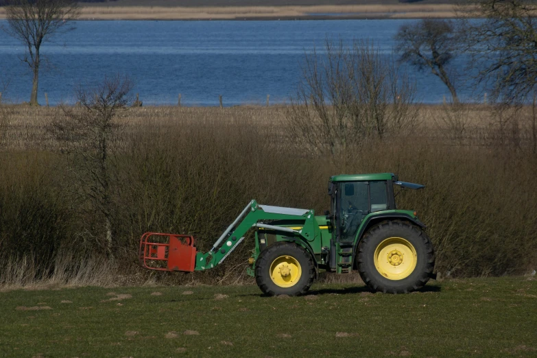 a tractor that is sitting in the grass, by Colin Middleton, shoreline, hedge, high res photograph, cane