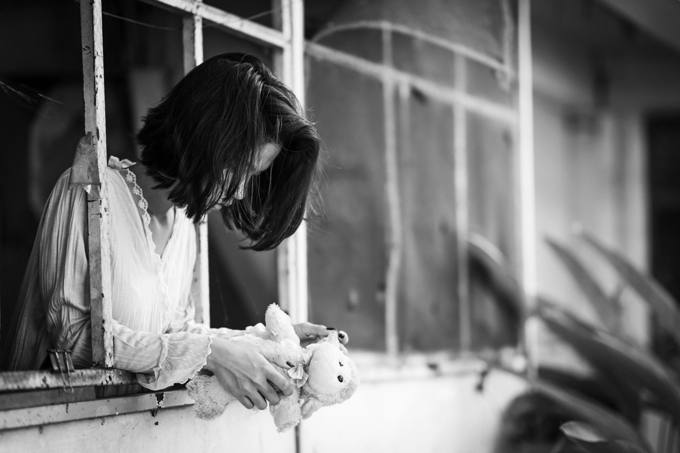 a black and white photo of a woman holding a teddy bear, by Lucia Peka, pexels contest winner, process art, dusty abandoned shinjuku, jonny greenwood, near a window, toys