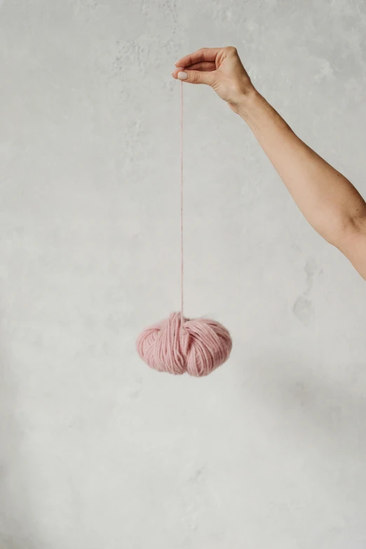 a woman holding a pink ball of yarn, inspired by Kim Tschang Yeul, hanging rope, faded pink, medium - shot, made of wool