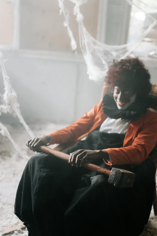 a woman sitting in a chair with a knife in her hand, pexels contest winner, vanitas, powerful male scarecrow, with afro, inside haunted house, b - roll