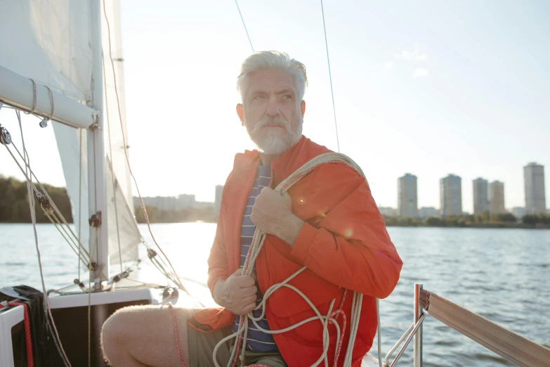 a man sitting on the bow of a sailboat, a photo, happening, silver hair and beard, avatar image, in style of joel meyerowitz, medium - shot