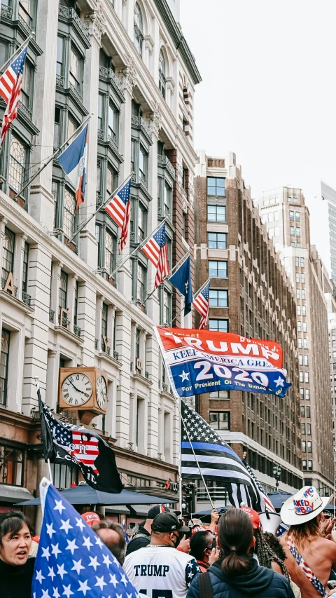 a crowd of people walking down a street next to tall buildings, by Drew Tucker, trending on unsplash, american flags, barron trump, lots of signs and shops, 🚿🗝📝